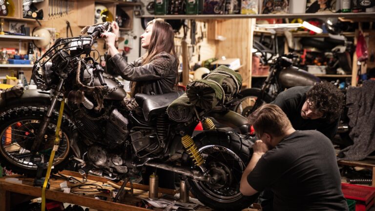 Mechanics collaborating on a custom motorcycle in workshop – precision Custom Car And Motorcycle Builds in progress.
