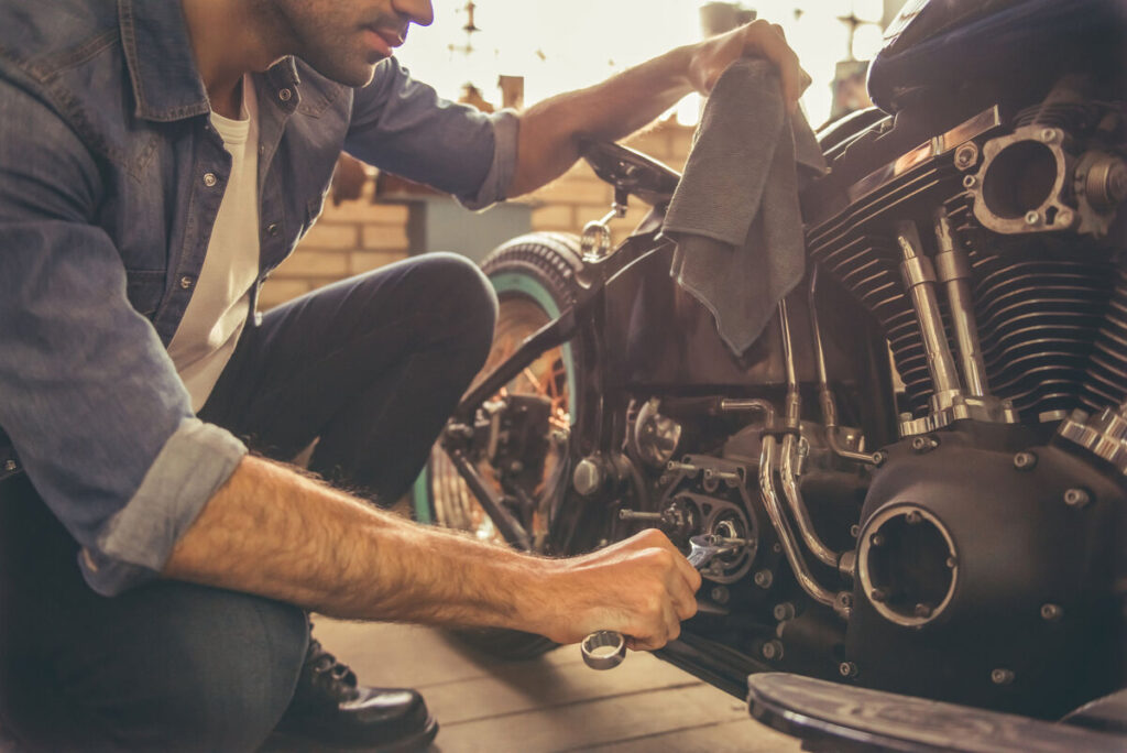 Mechanic repairing and polishing a custom motorcycle at an automobile custom shop.