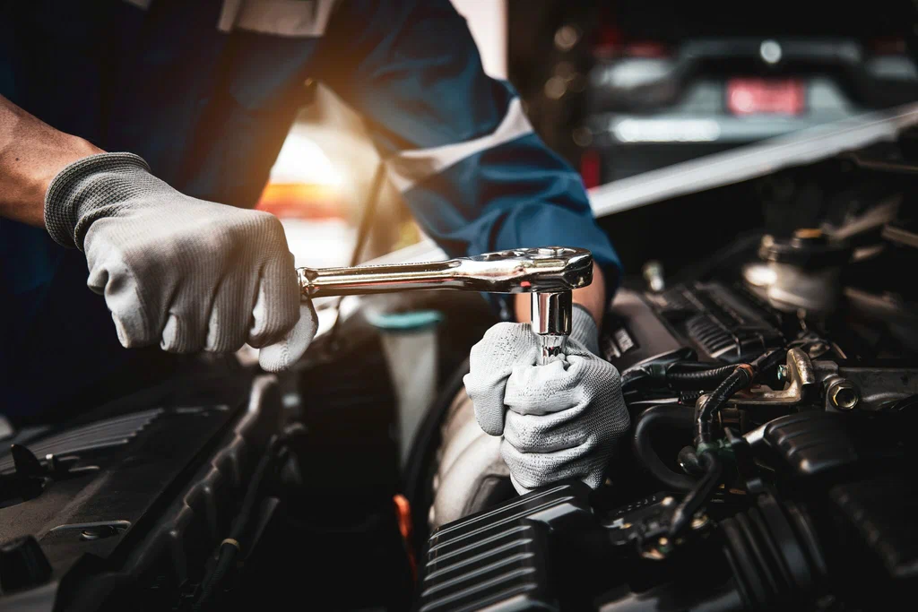 Mechanic using a wrench to repair a car engine at an automobile custom shop.